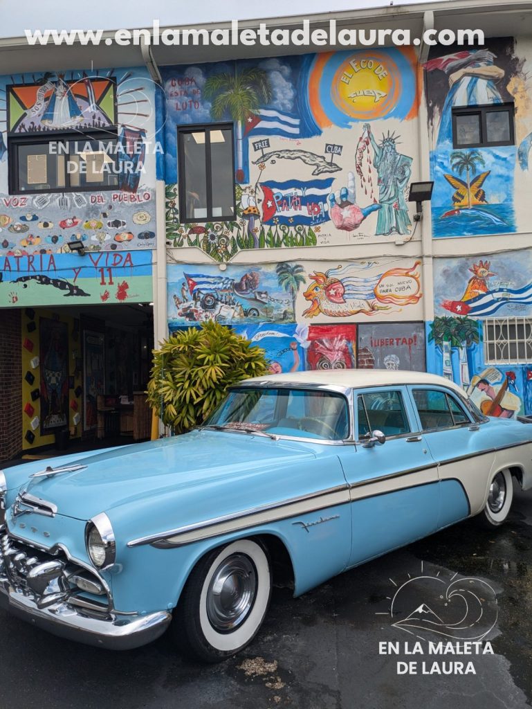 Coche clásico azul aparcado frente a murales cubanos en Little Havana